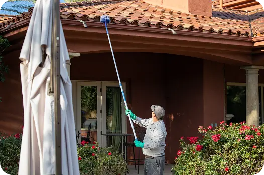 technician de-webbing all eves and corners to prevent spider infestations