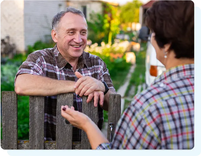 neighbors talking to each other over a fence